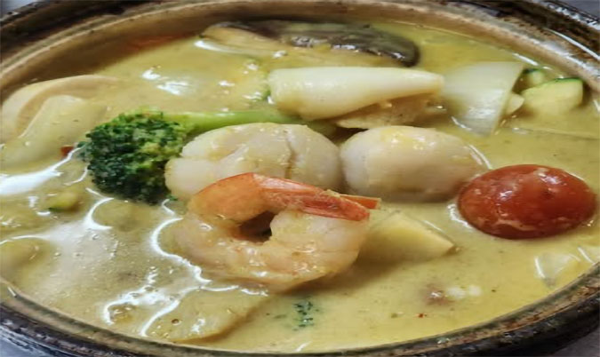 Seafood combination with signature yellow curry sauce in clay pot